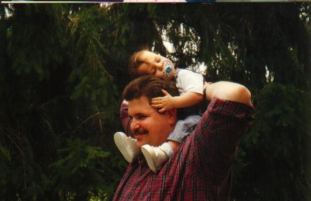 Chris with his son asleep on his shoulders.